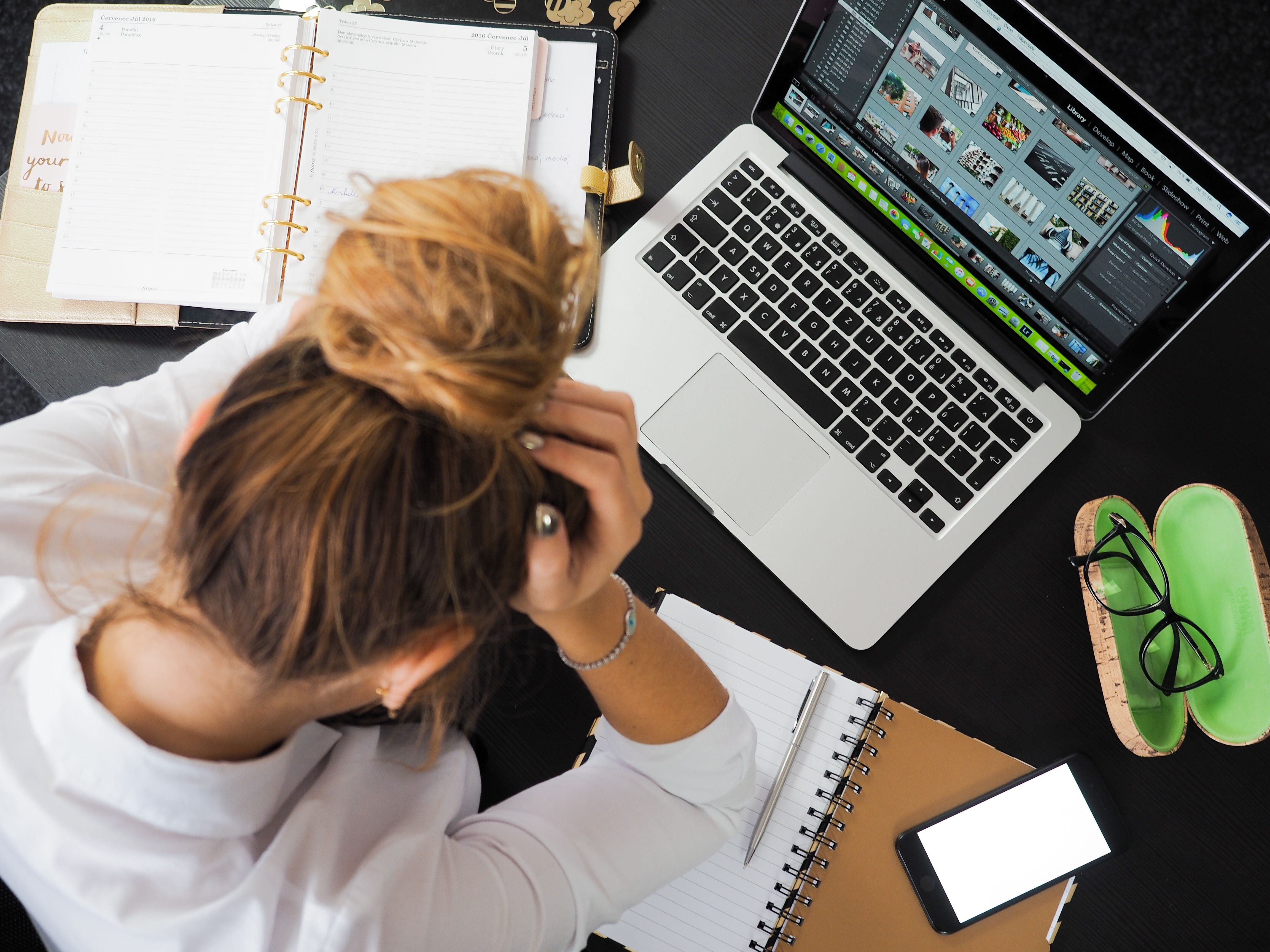 Overwhelmed mother at her desk
      with a laptop, planner, and phone