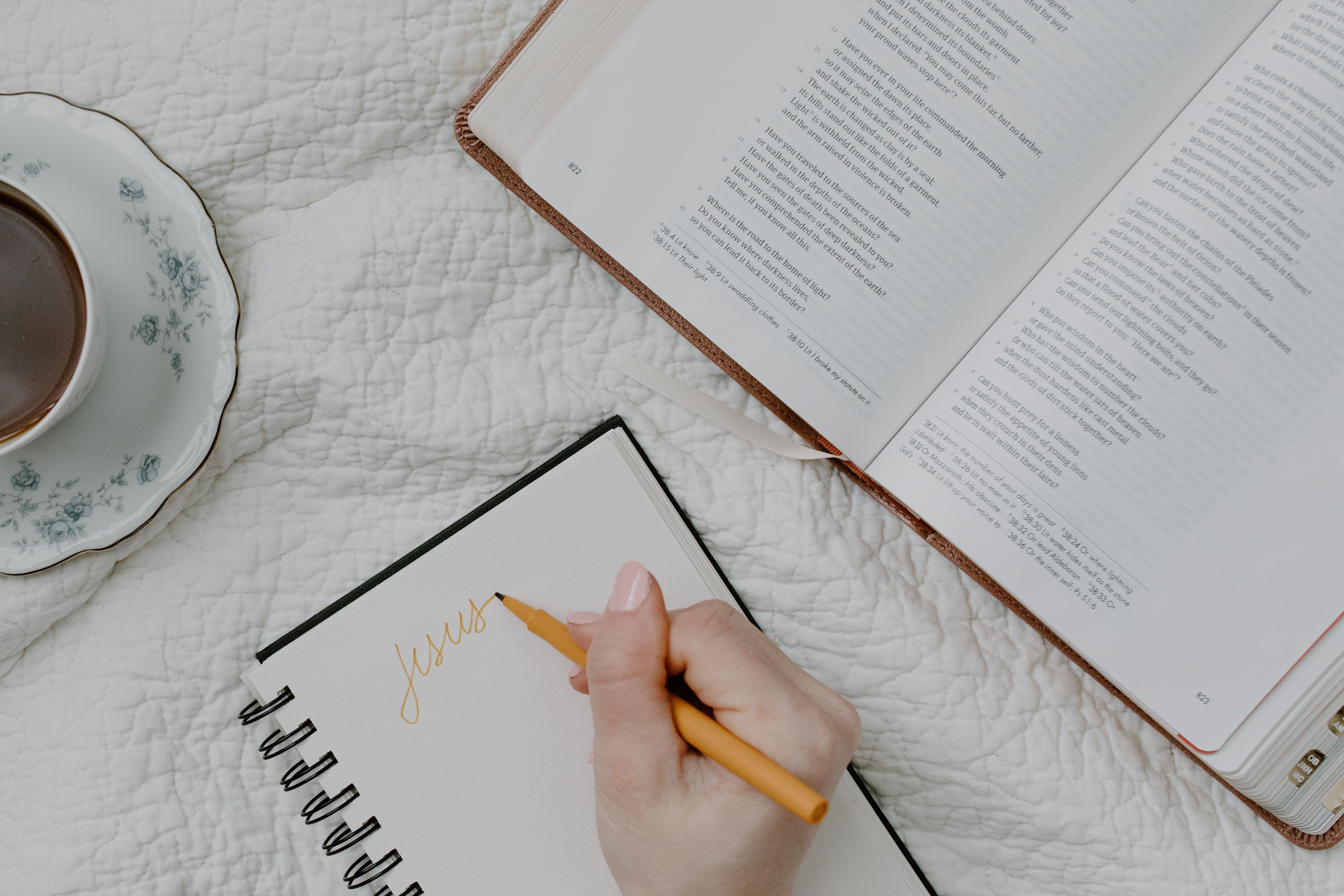 Writing in a journal beside
      an open Bible and coffee